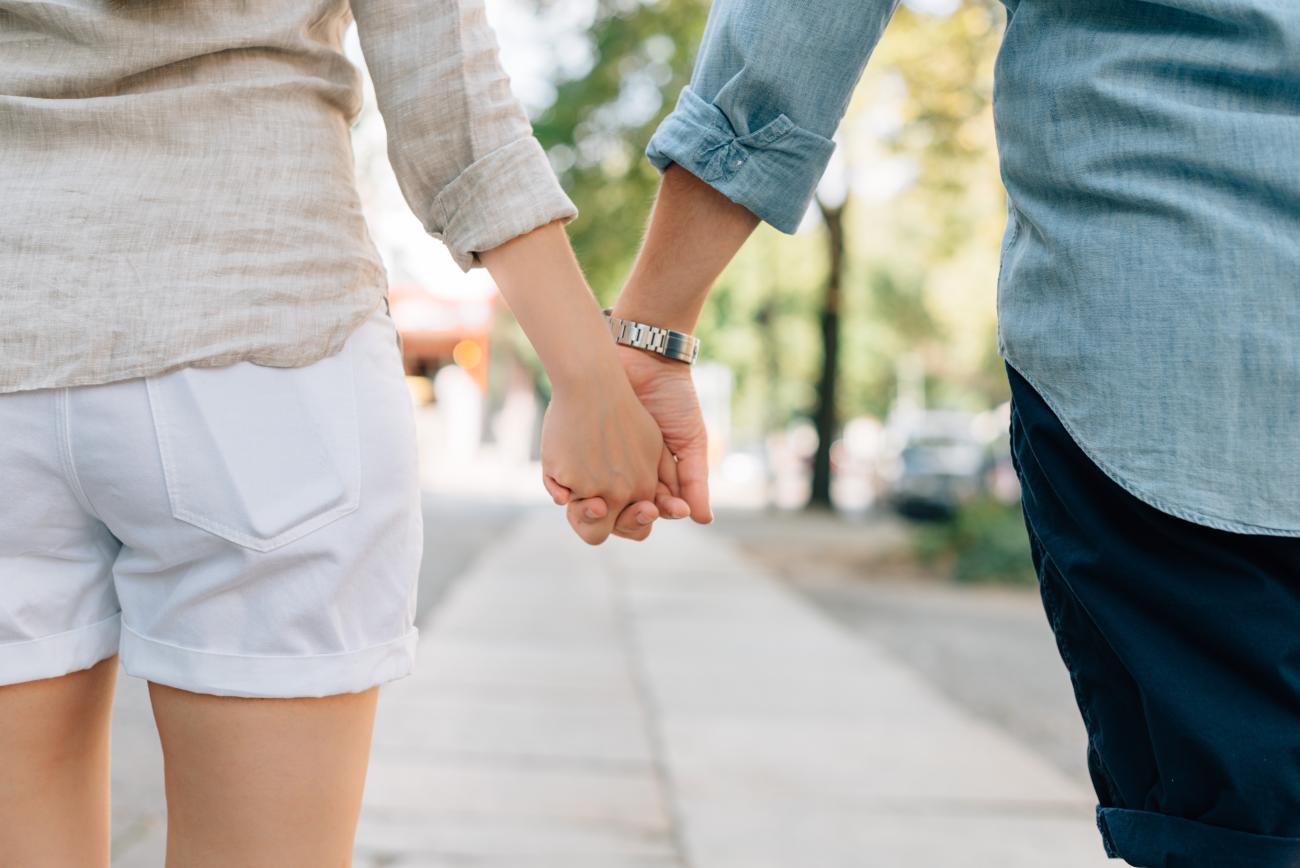 Couple holding hands as they look down the street