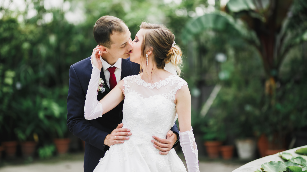 a beautiful bride and groom embrace and kiss on their wedding day outdoors