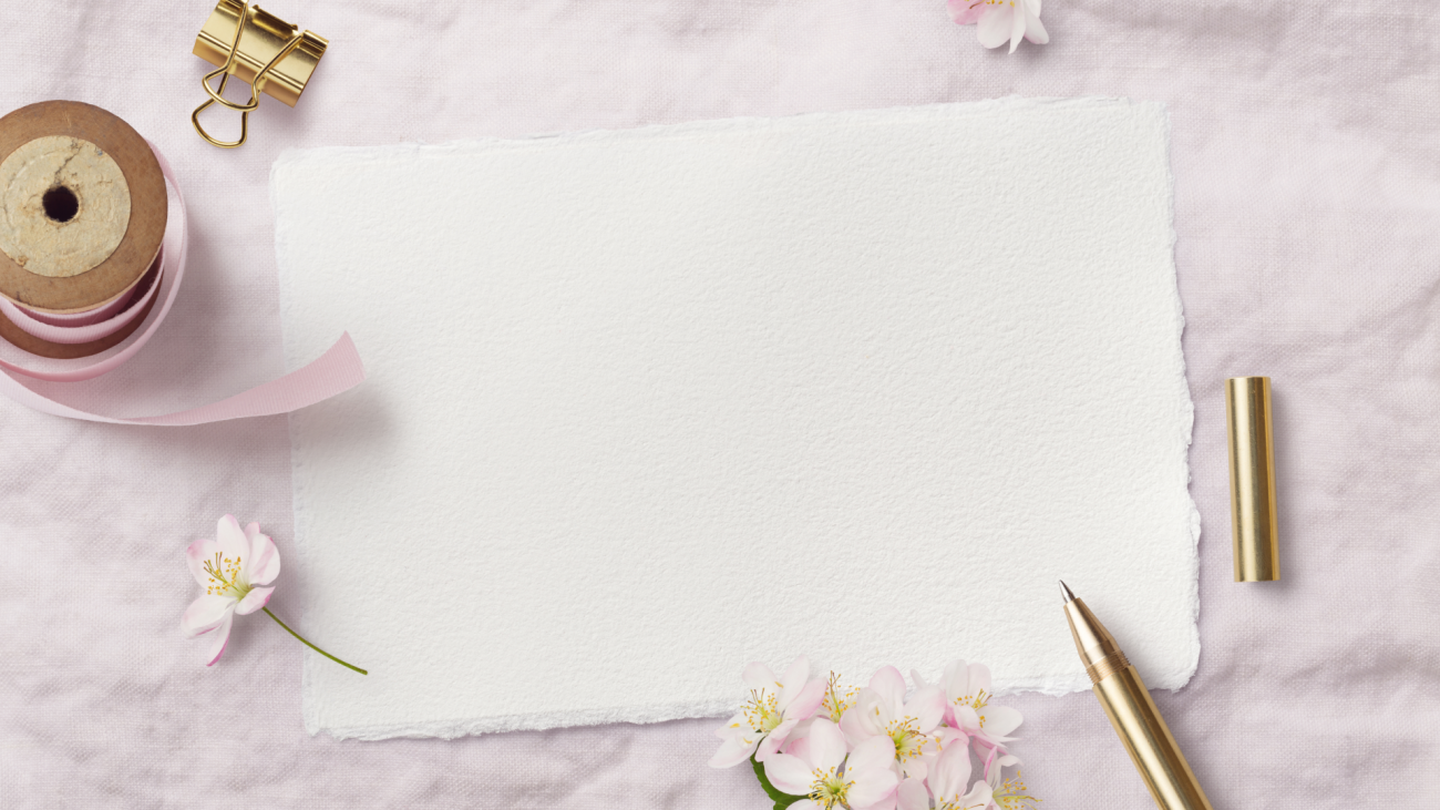 blank wedding stationery sits in with flowers and a pen