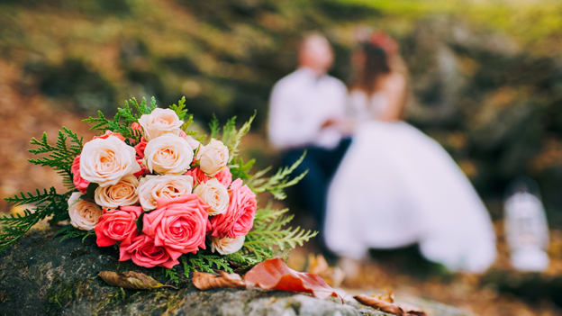 bouquet in foreground with bride and groom in background