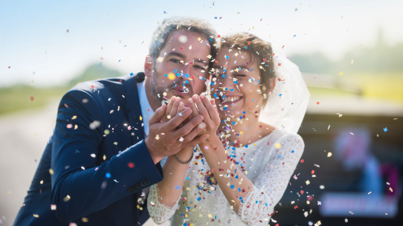 a bride and groom blowing confetti on their wedding day