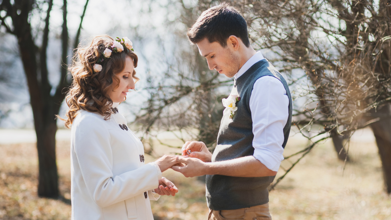 a bride and groom exchanging rings during their casual outdoor wedding ceremony