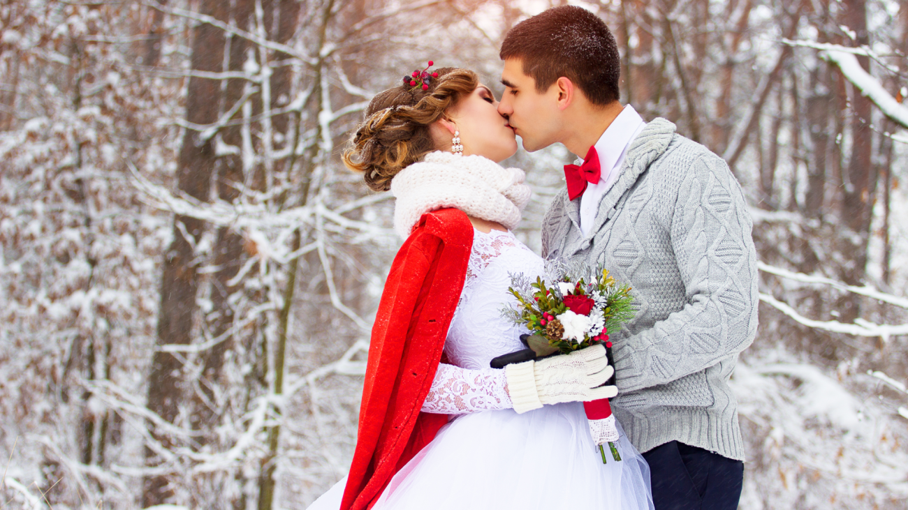 a bride and groom kiss in the woods during their winter wedding ceremony