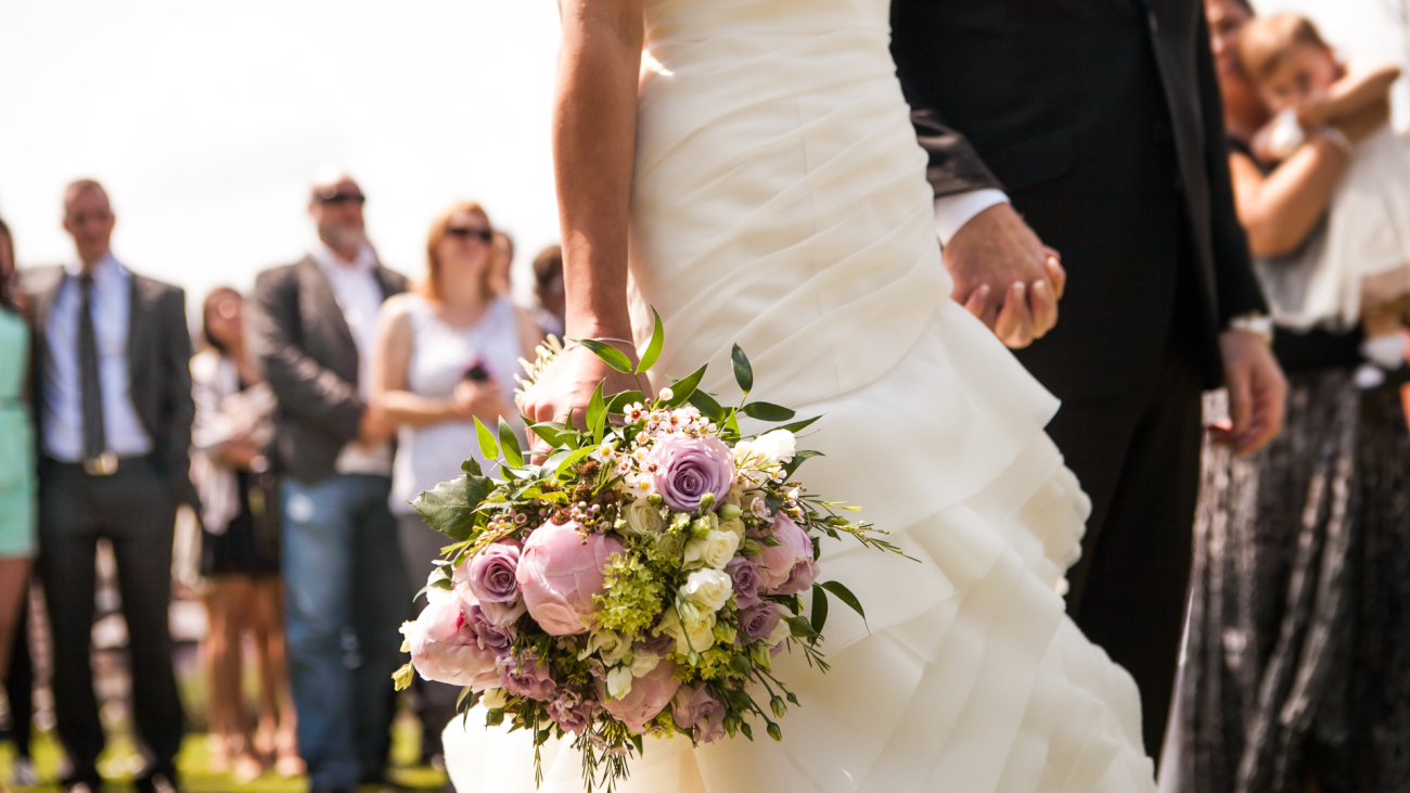 a bride and groom on their wedding day with guests in the background