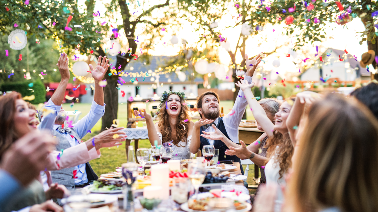 a bride and groom celebrating with guests at their backyard wedding reception