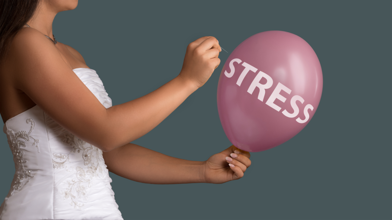 a bride wearing a wedding dress, who is popping a stress balloon with a pin