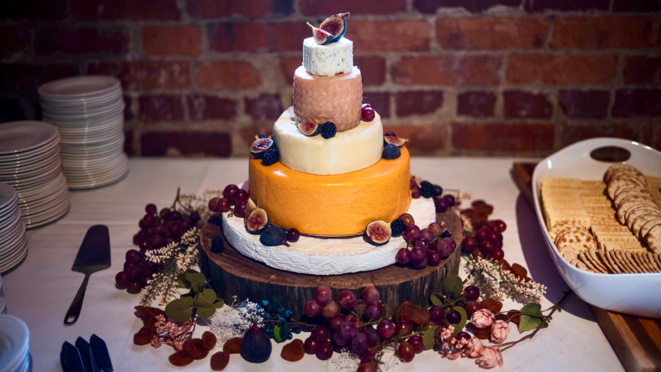 a cheese wheel wedding cake with grapes and crackers
