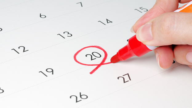a person circles a date on a calendar with a red pen