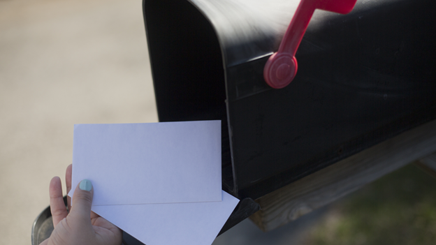 a close-up of a person's hand putting letters in a mailbox