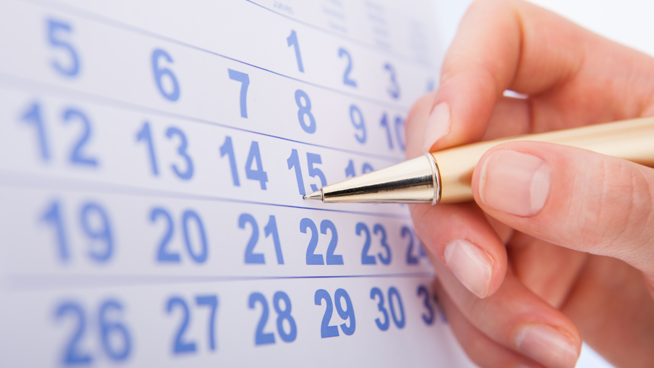 a closeup of a woman's hand marking date 15 on a calendar