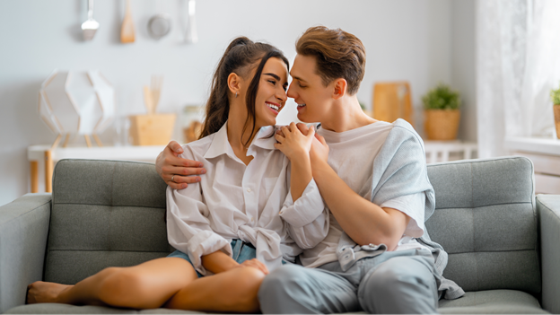 a couple cuddles on couch and are about to kiss