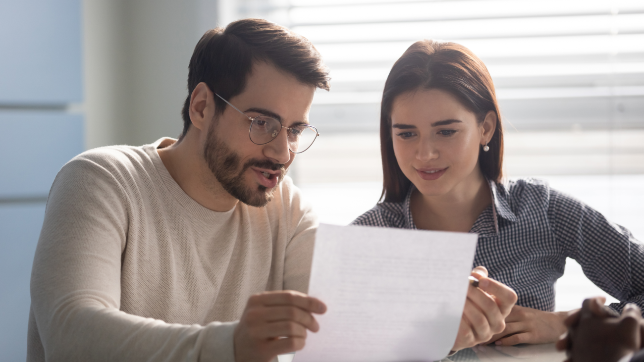 a couple looks at a piece of paper while sitting at a table