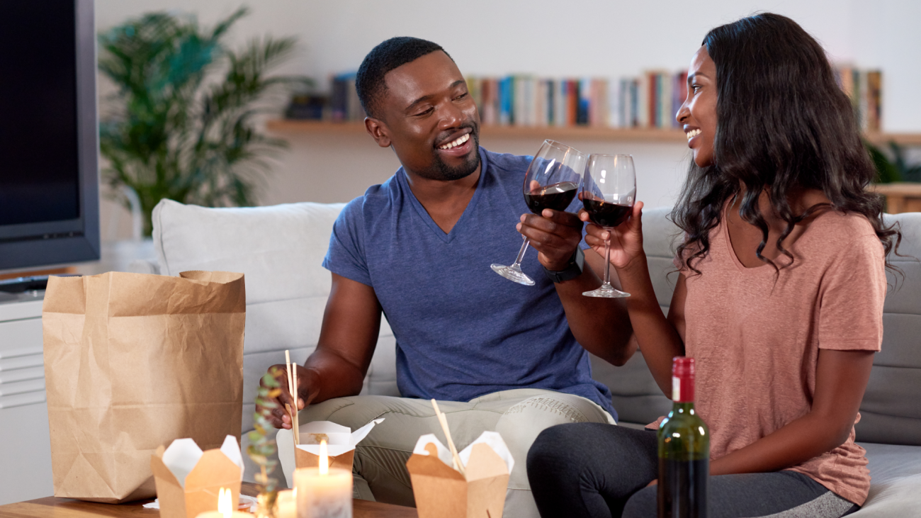 a couple has a date at home, where they eat takeout and drink wine