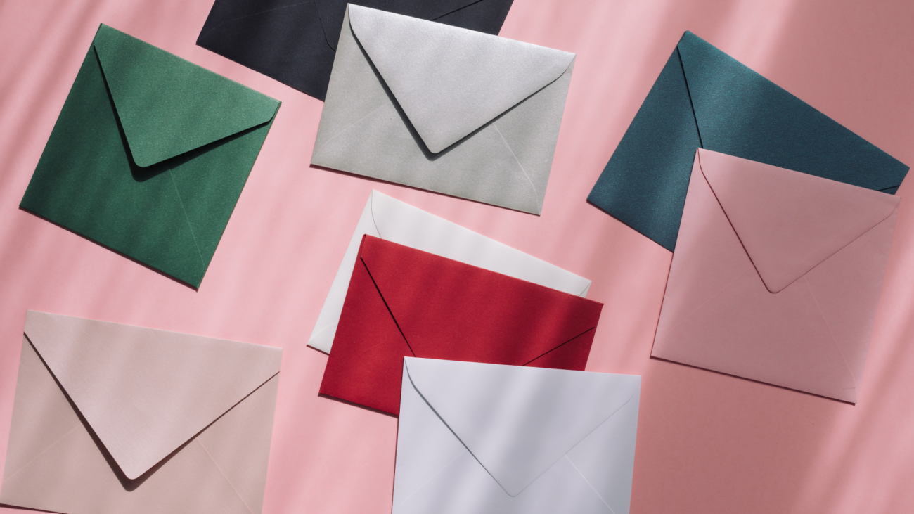 a collection of different-colored envelopes on a pink background