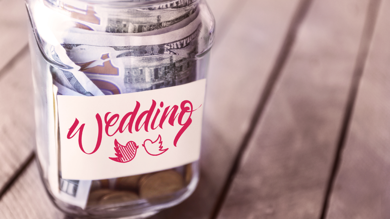 a glass jar filled with dollars and coins, labeled “wedding budget”