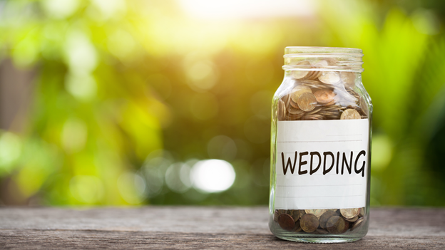 a glass jar filled with coins, which represents a wedding budget