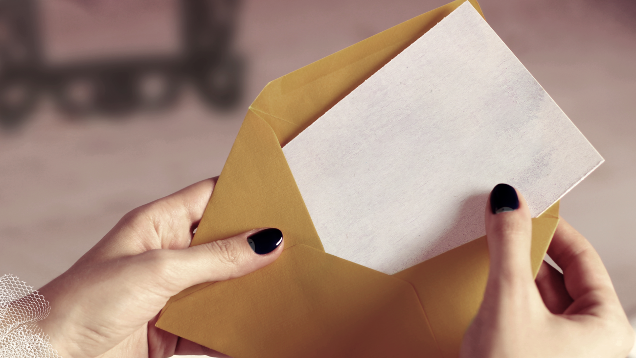 a close-up of a person’s hand opening a card in a brown envelope