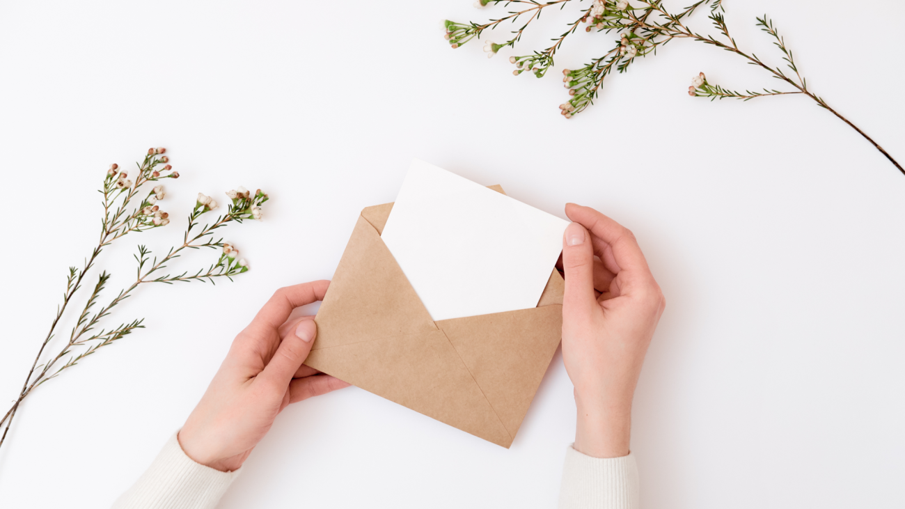 a hand takes a small piece of paper, possibly a wedding invitation, out of a brown envelope
