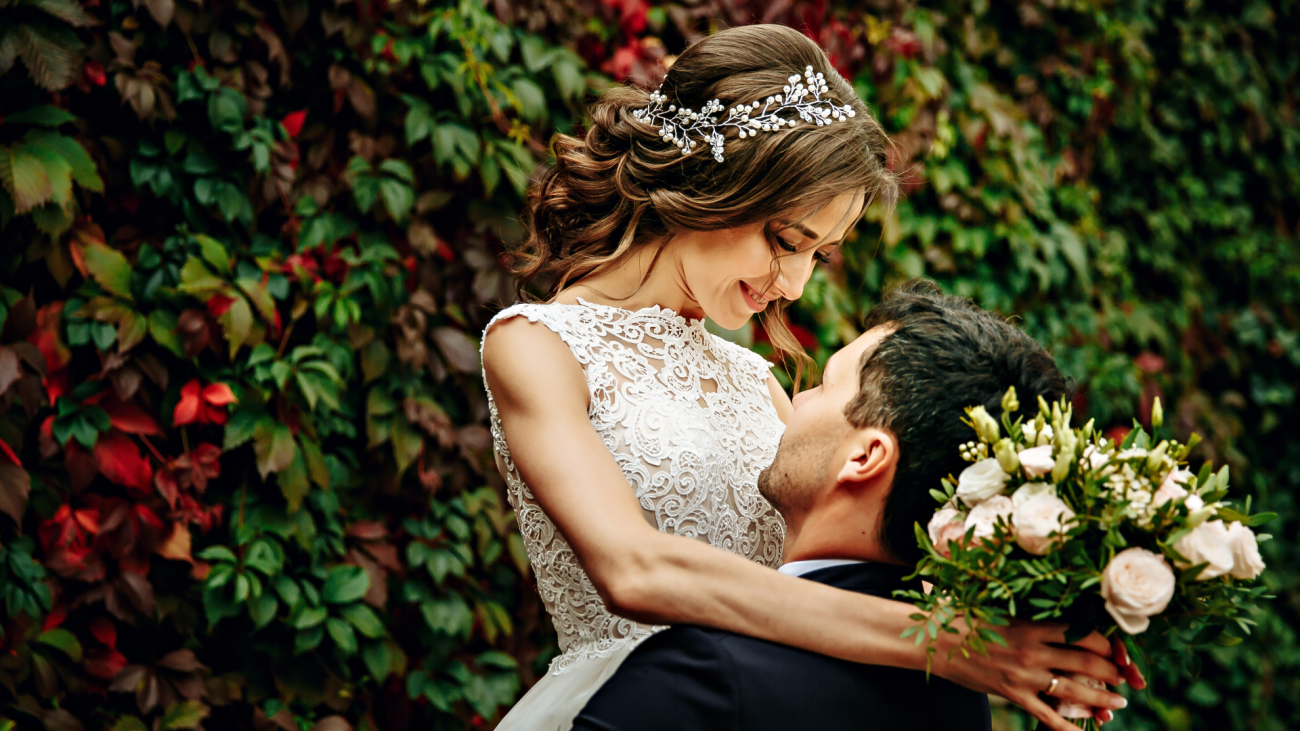 a groom lifts up his bride in his arms as she looks down upon him and smiles