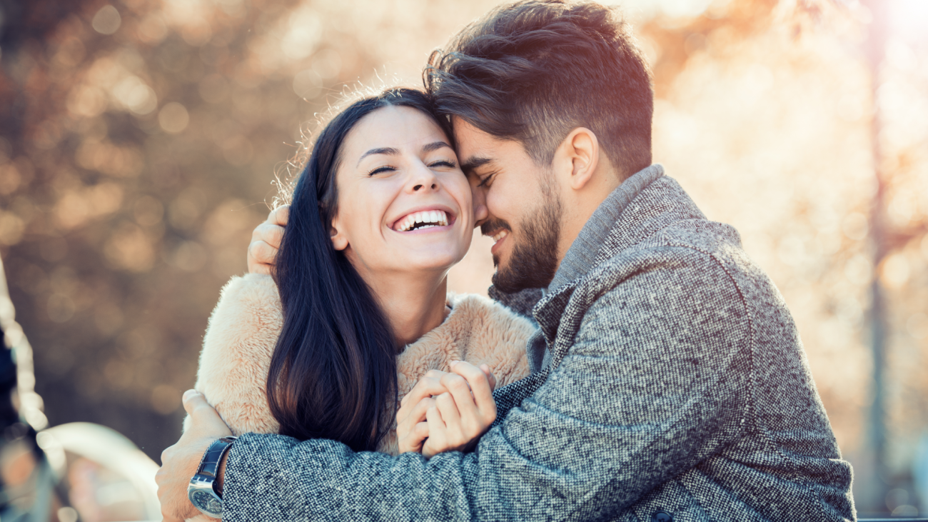 a happy couple smiling and embracing outdoors in romantic setting