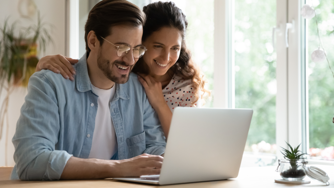 a happy couple watching a video on their laptop computer