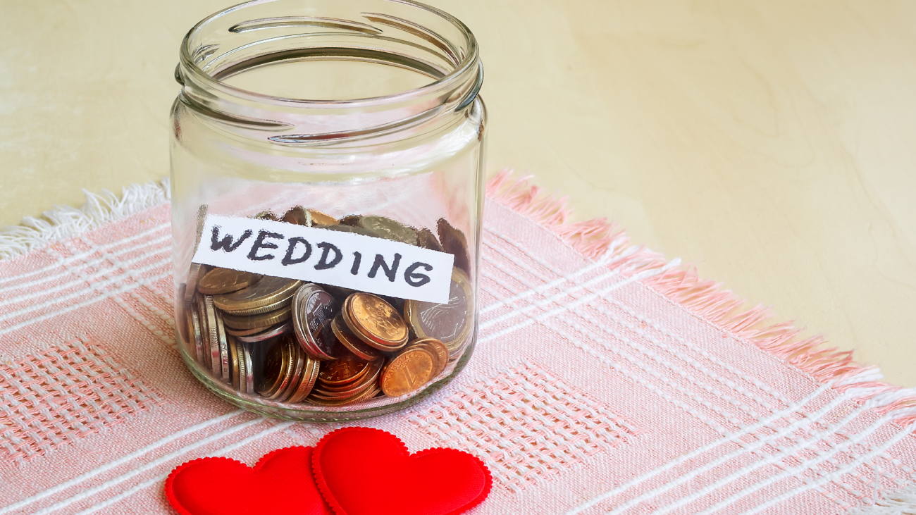 a jar with a “wedding” label on it sitting next to two silk hearts