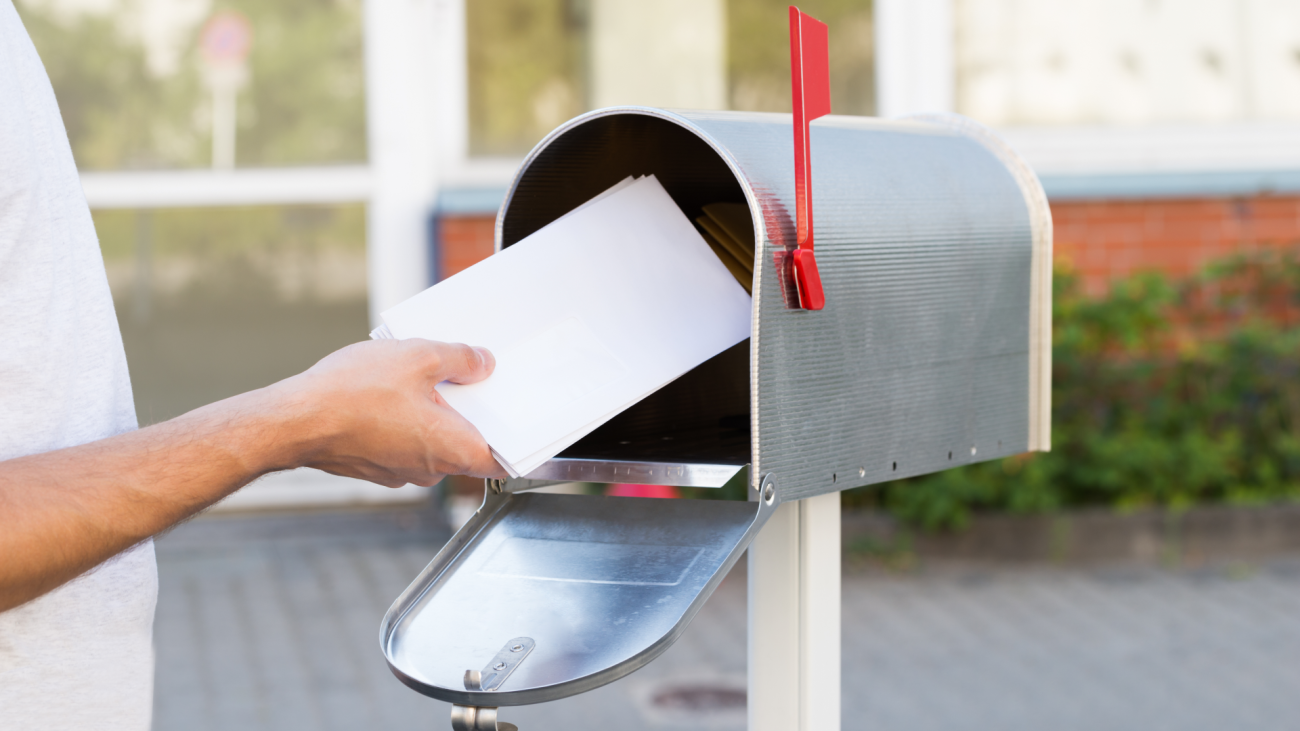 a man putting a stack of letters in the mailbox