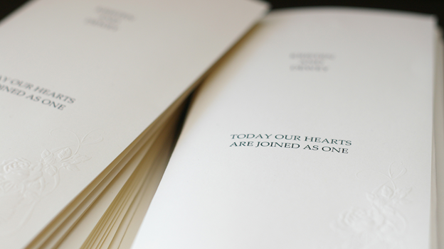 a pile of wedding programs with the words “TODAY OUR HEARTS ARE JOINED AS ONE" on front cover