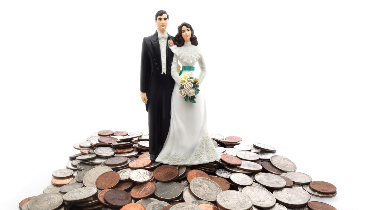 a plastic wedding couple standing on a pile of coins