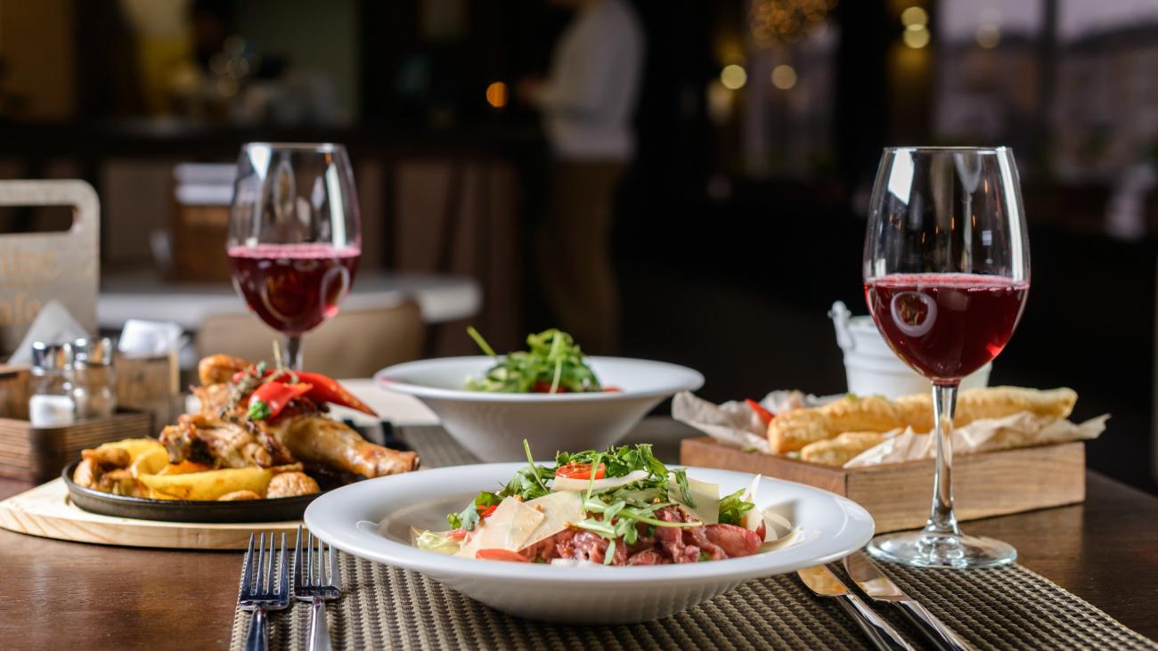 a romantic fancy dinner with wine, pasta, salad, and breadsticks on a table