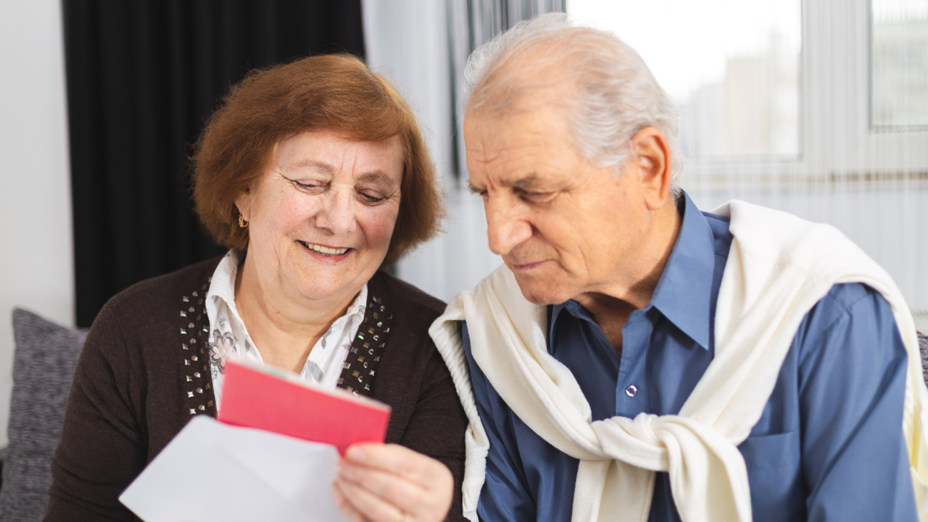 a senior couple opens a card they received in the mail