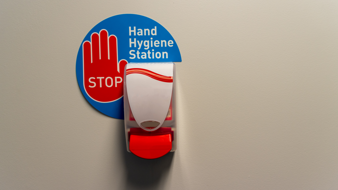 a hand sanitizer station on wall displaying the words “Stop” and “Hand Hygiene Station”