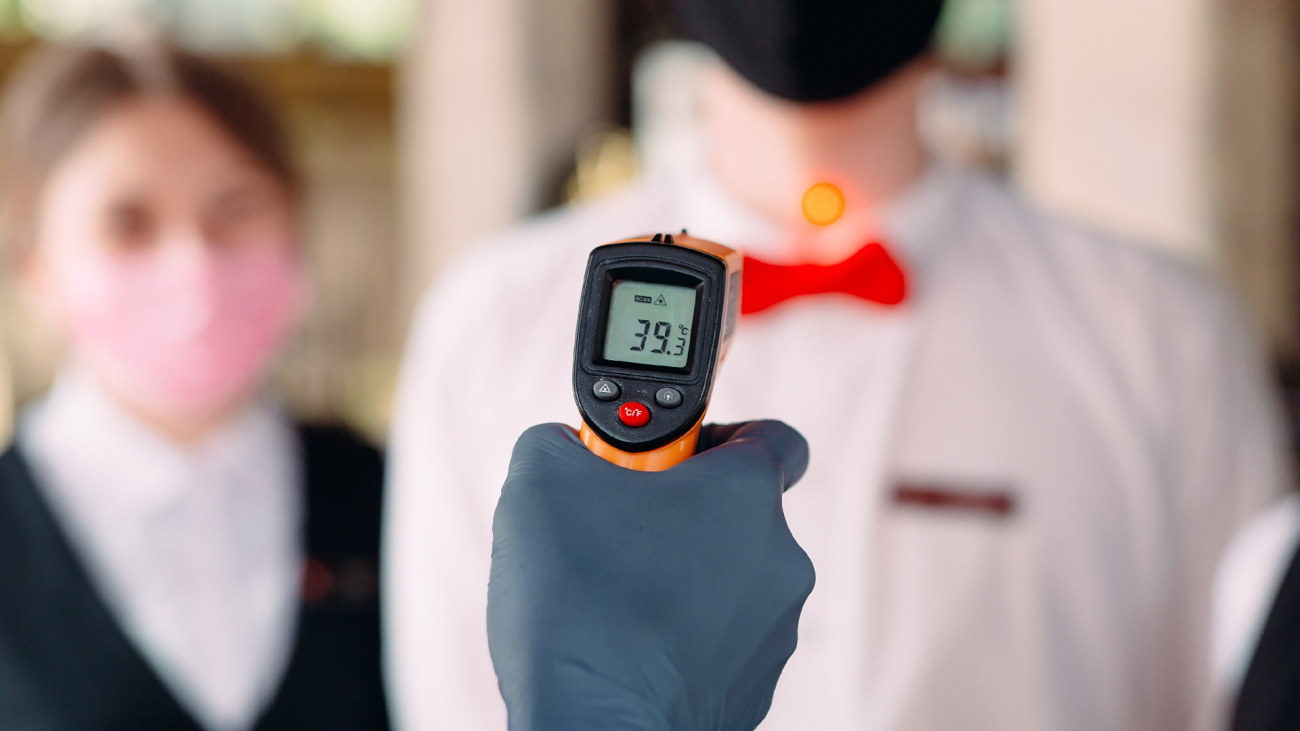 the manager of a restaurant or hotel checks the body temperature of the staff with a thermal imaging device