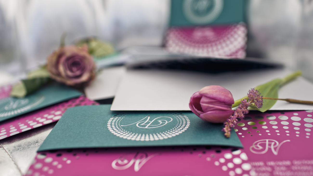 tulips and lavender lie on a collection of green and pink invitation cards
