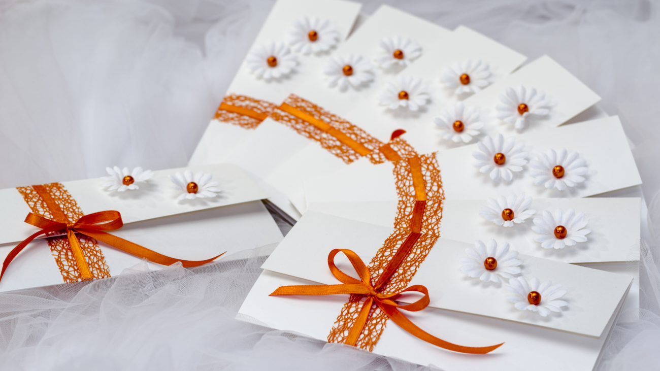 a set of unique handmade wedding invitations with flower embellishments sitting on tulle fabric