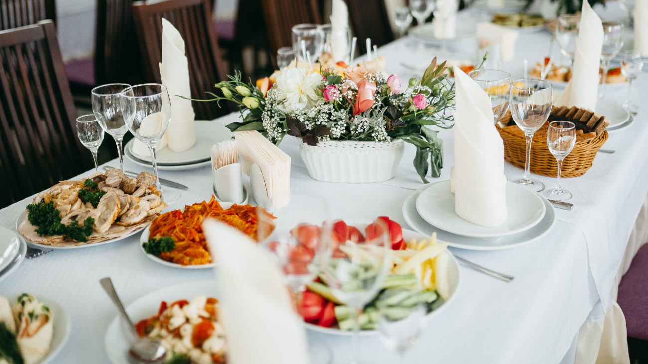 a wedding banquet featuring food on a table with a flower centerpiece