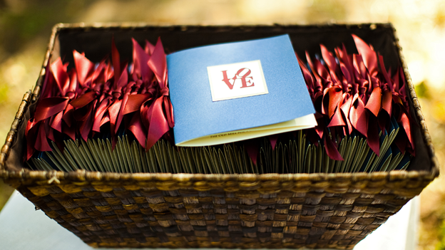 wedding ceremony programs sit in a basket while one program, labeled with the word “love,” sits on top