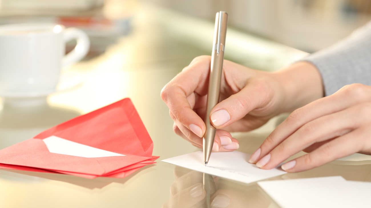 a woman handwrites a greeting card with a pen