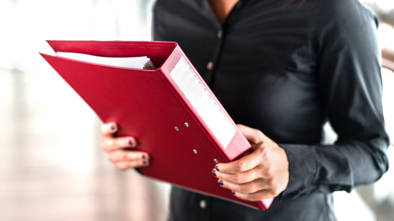 a woman holds a binder filled with paper  documents