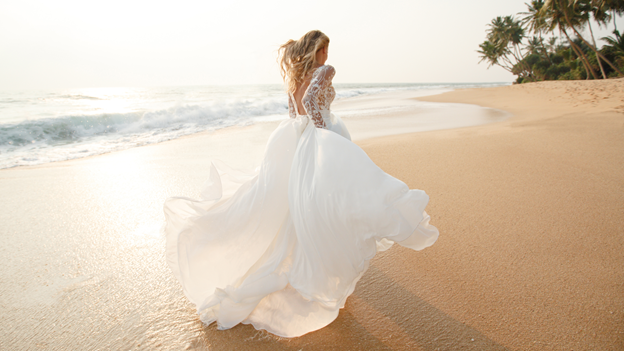 woman in wedding dress running down the beach