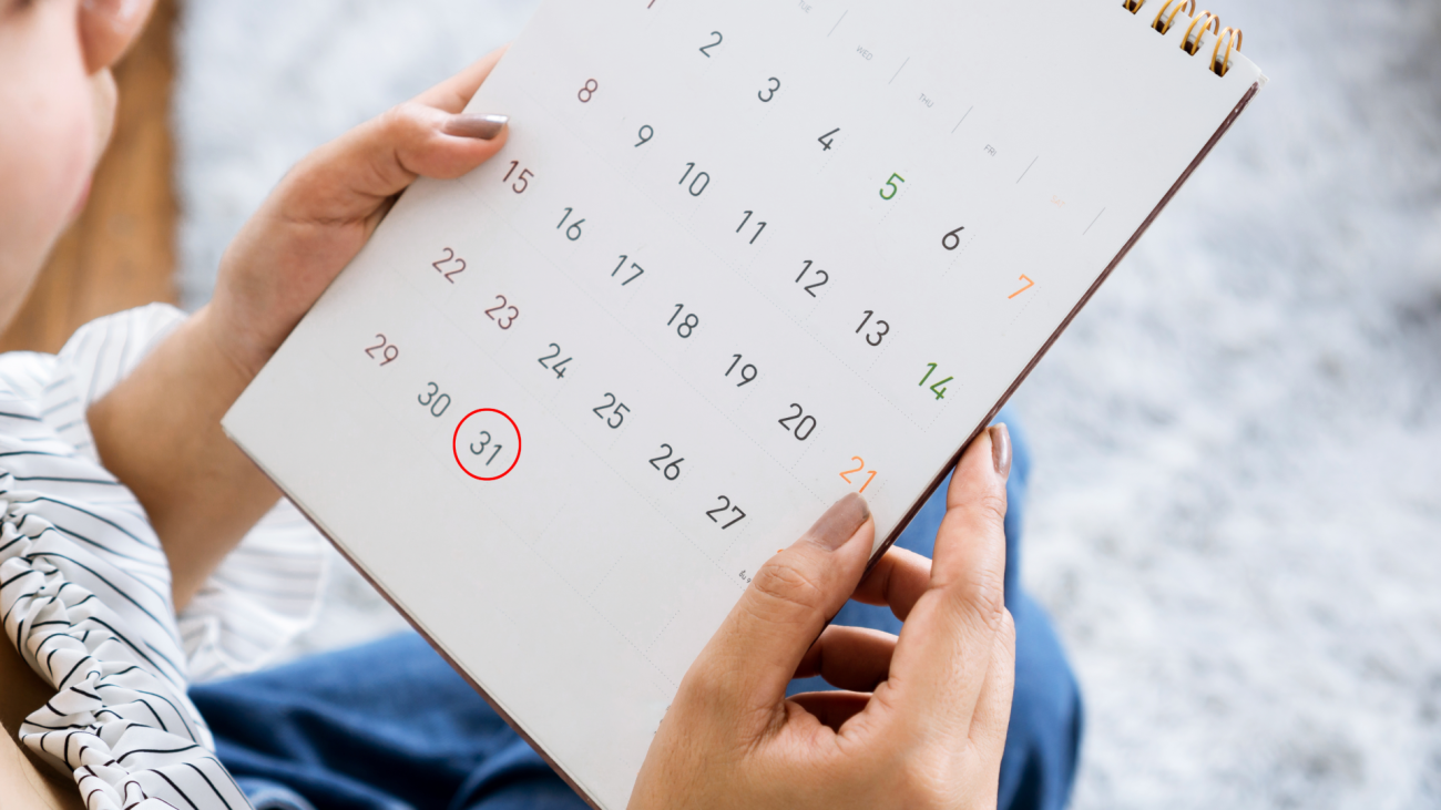 a woman looks at a calendar and circles the 31st date