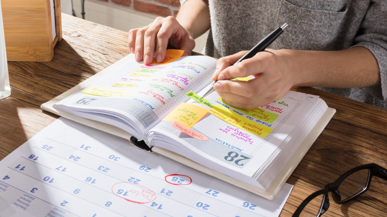 a woman makes notes of appointments in her planner