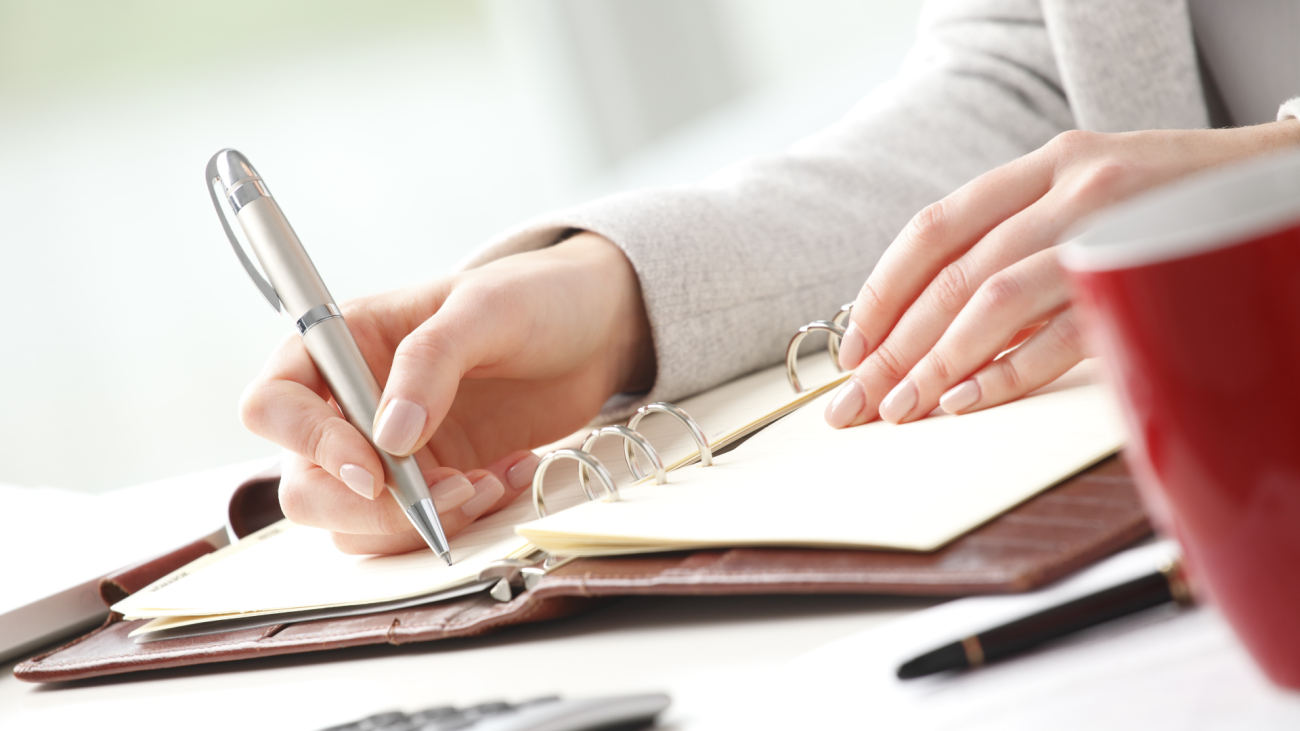 a woman making a list with cup of coffee by her side