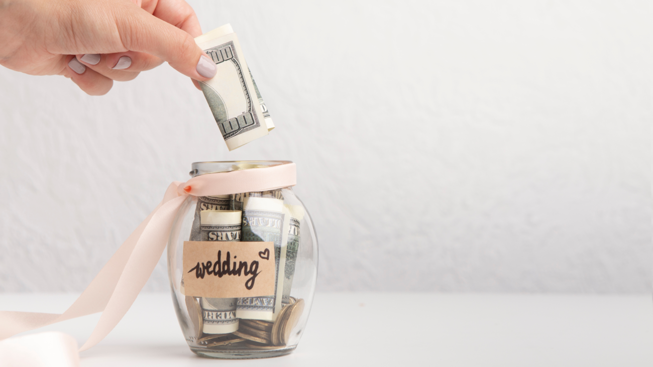 a woman puts money in a jar labeled with “wedding” to signify her wedding budget