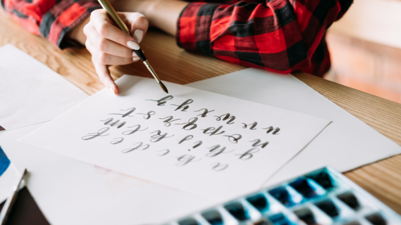 a woman writes script font with a brush