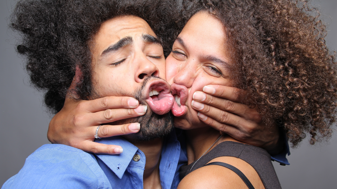 a couple makes funny faces as they kiss