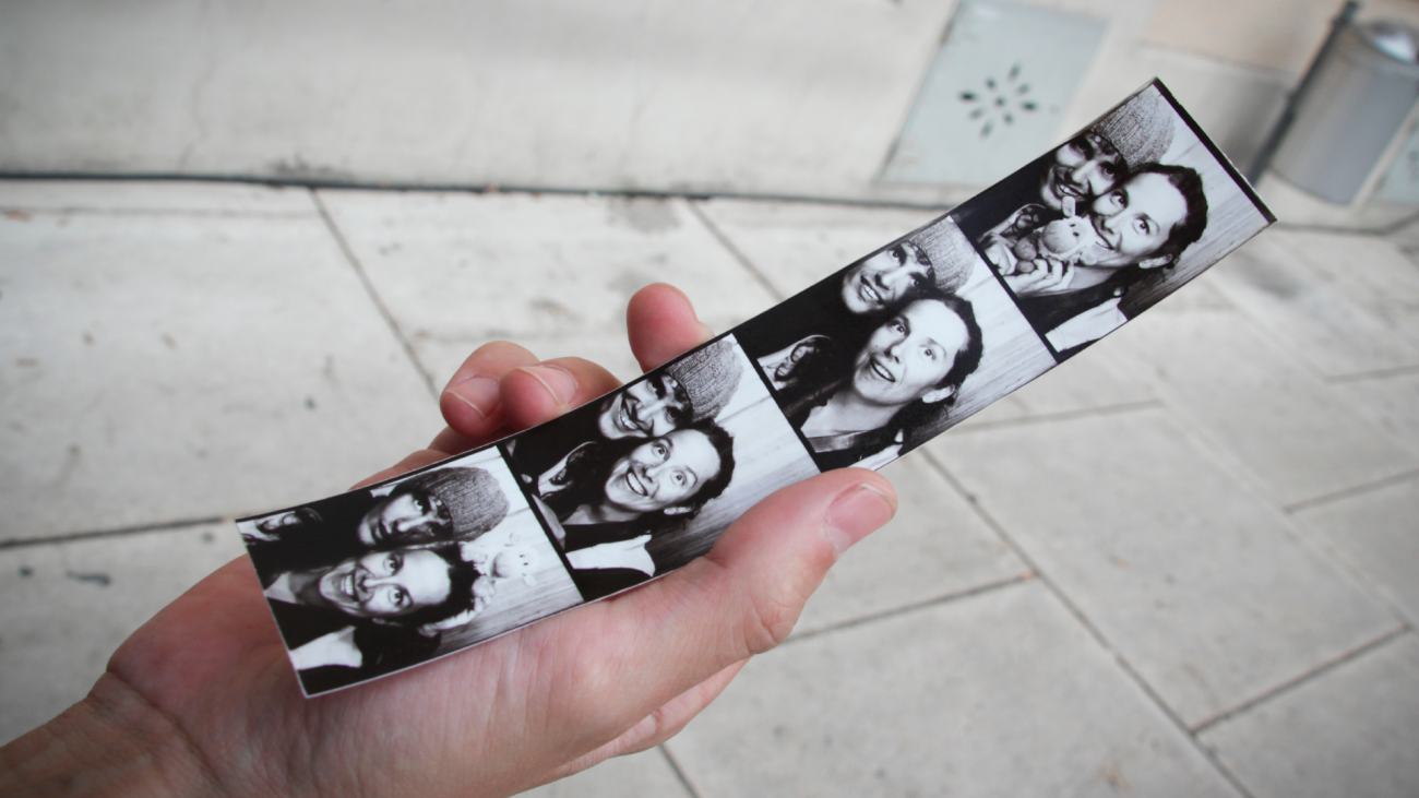 a hand holding a photobooth strip with the photos of a young couple