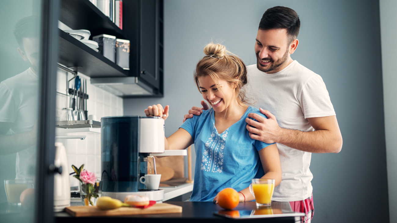 a happy couple makes coffee in their kitchen