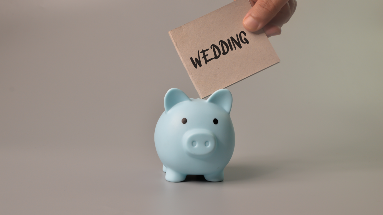 a hand puts a wedding note in a piggy bank