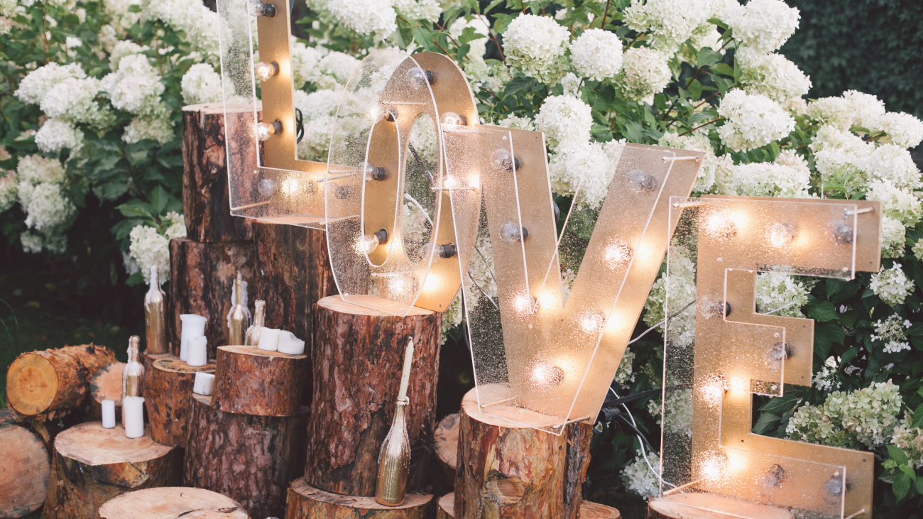 a decorated meadow for a wedding ceremony, featuring the word “love” written in lights